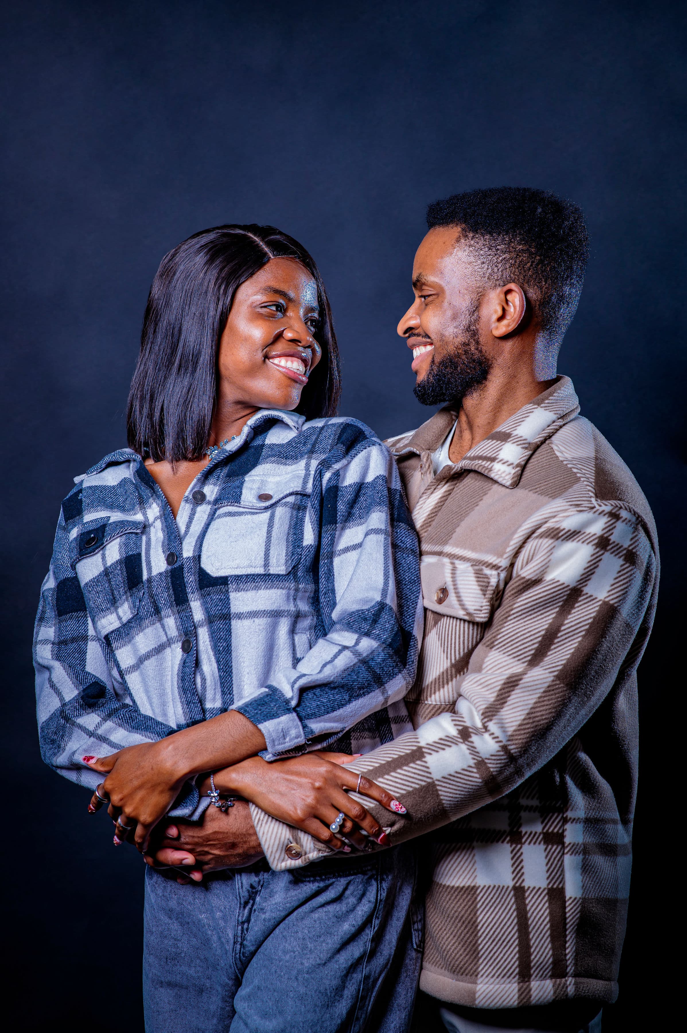 David embracing Esther from behind in matching plaid, sharing a look