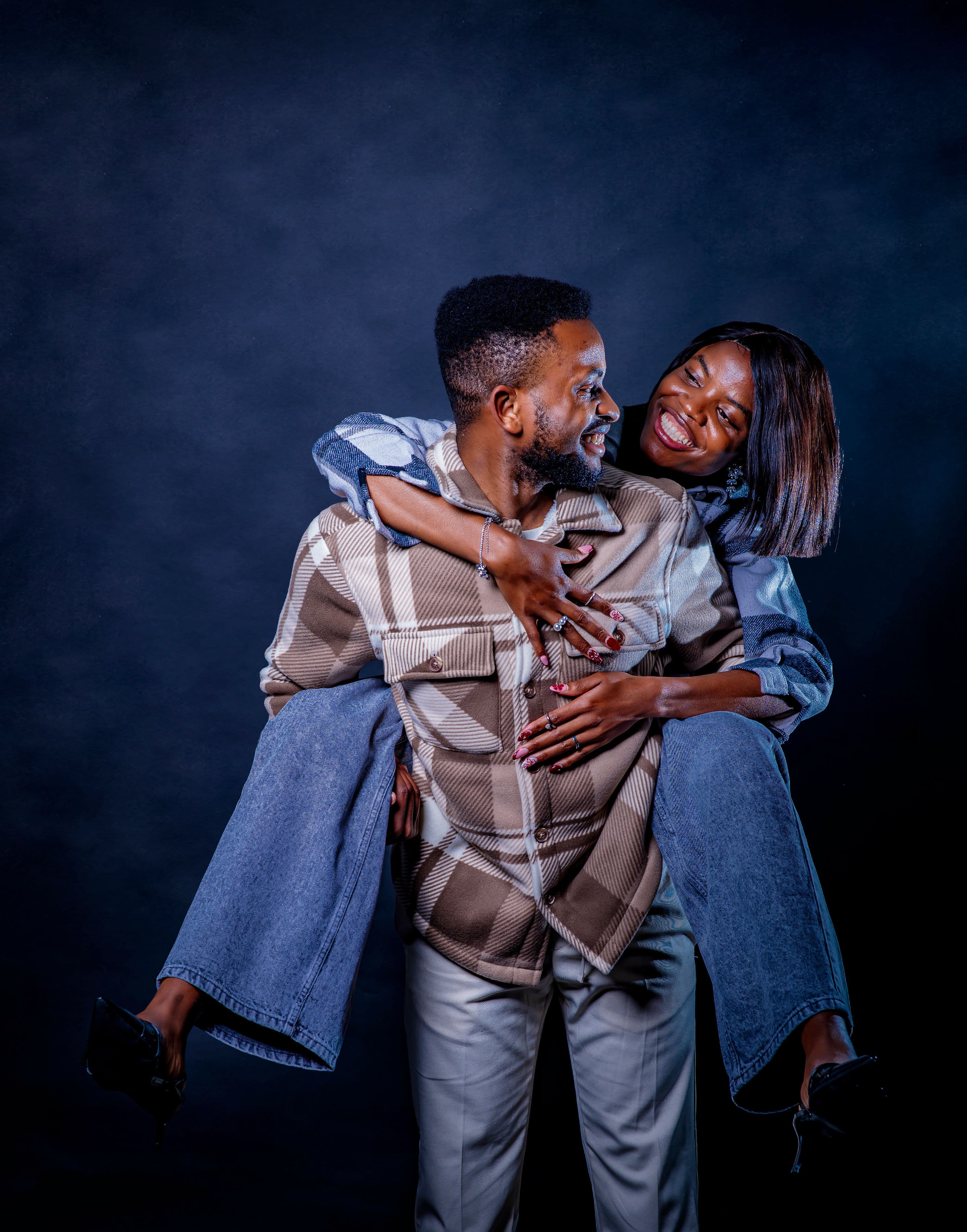 Esther riding piggyback on David, both laughing joyfully