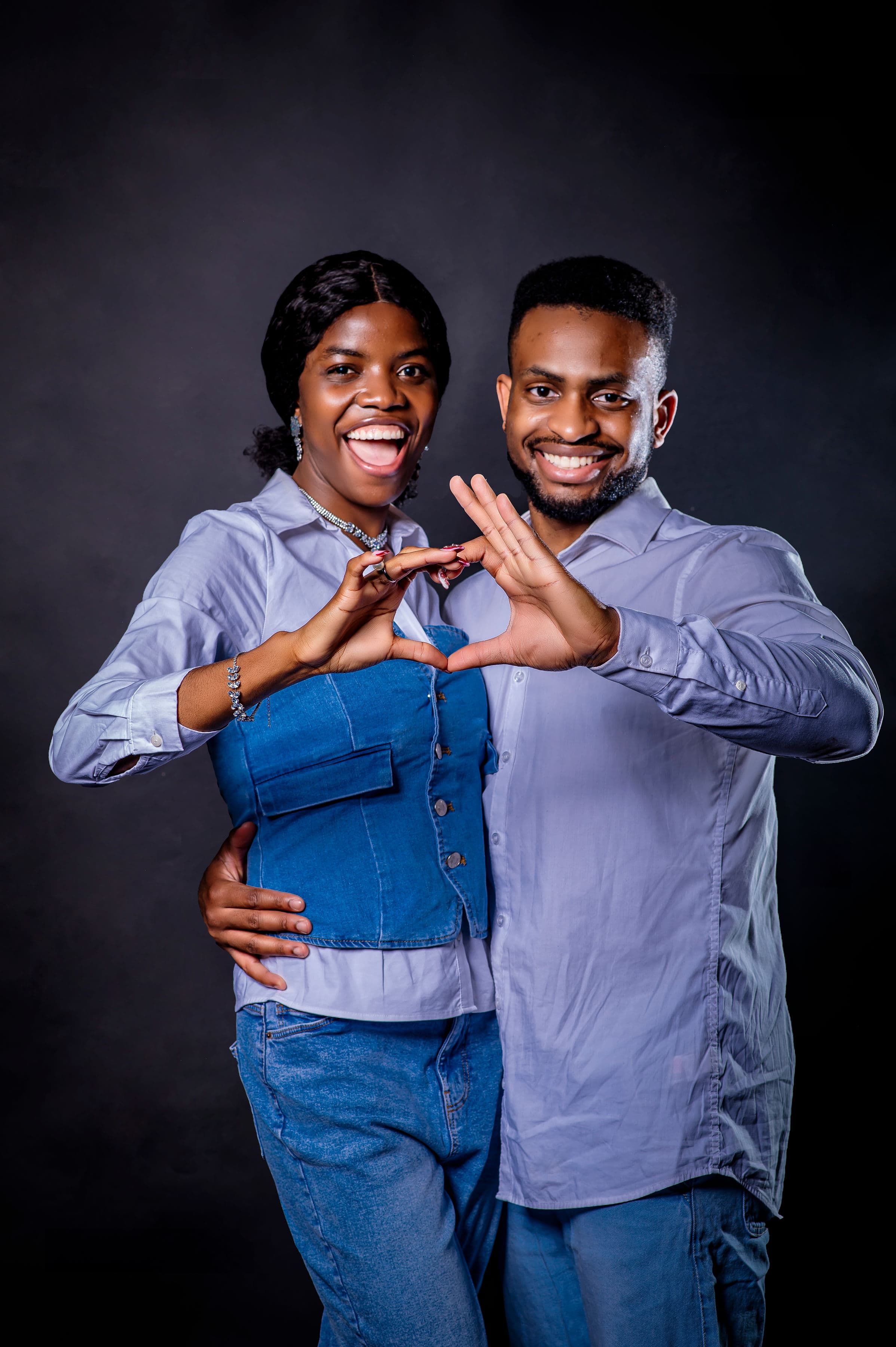 David and Esther forming a heart with their hands, beaming at the camera