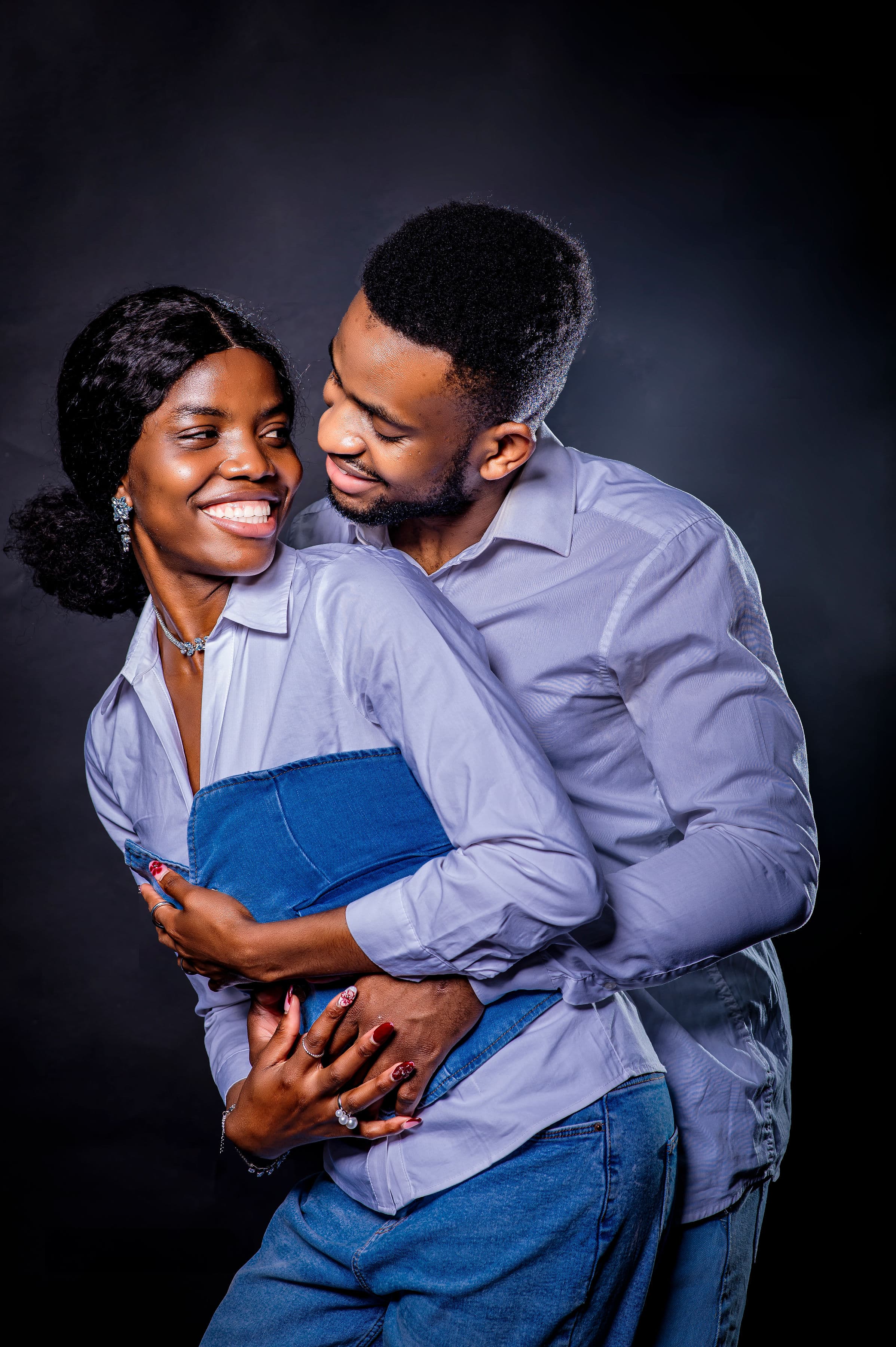 David embracing Esther from behind in denim and pale blue, both smiling