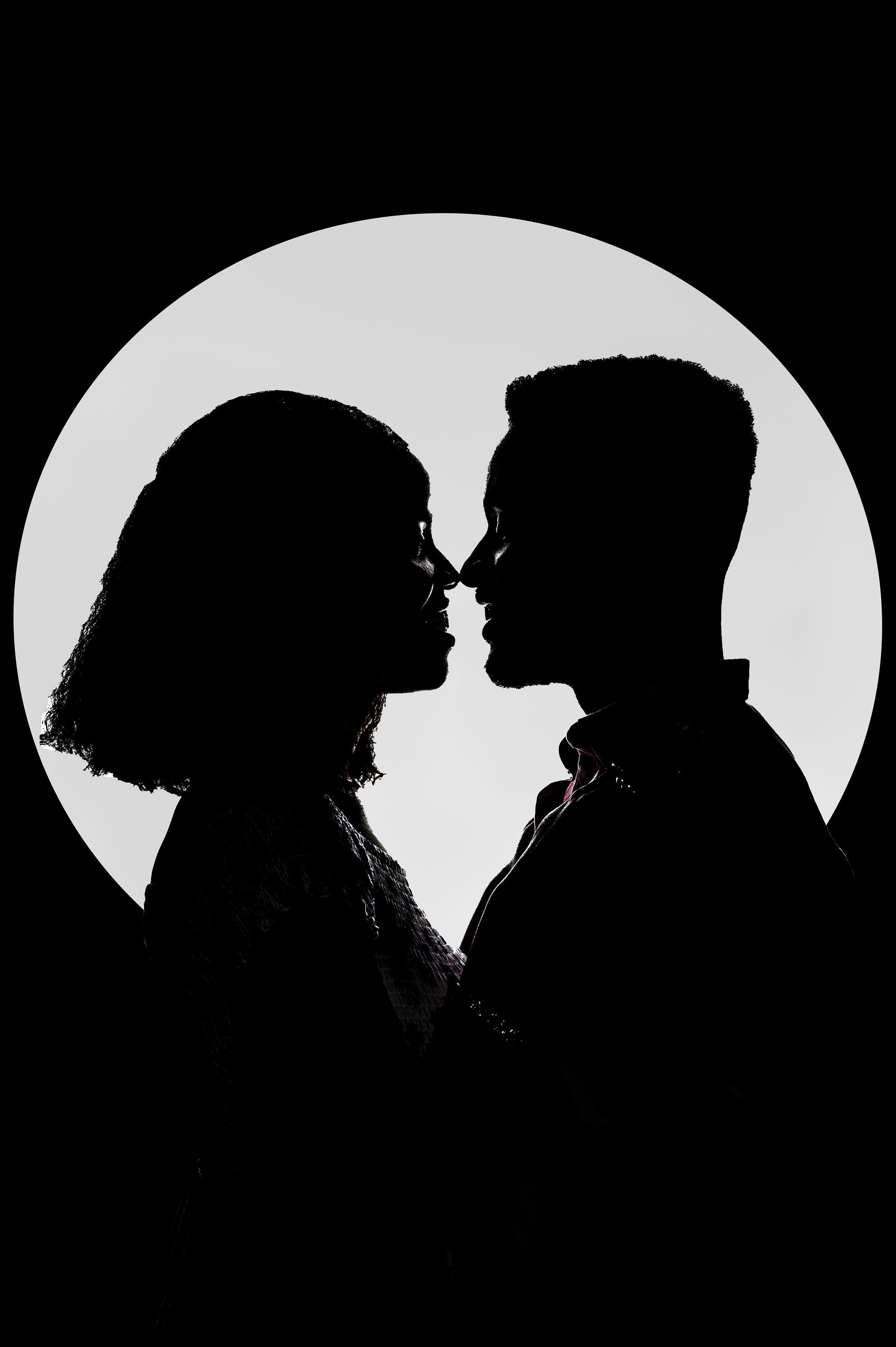 Silhouette of David and Esther nose to nose inside a ring of light