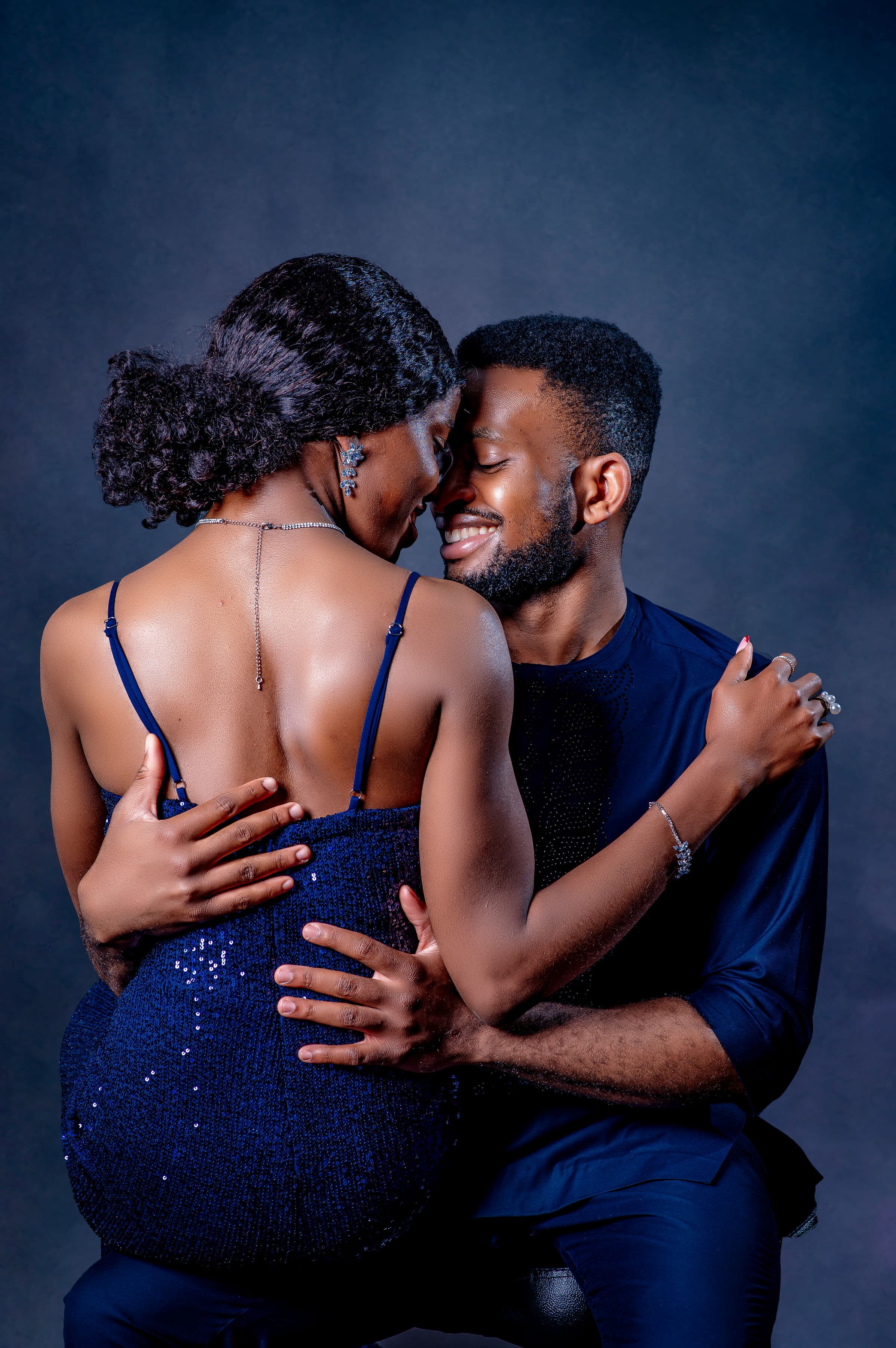 David and Esther in navy attire, foreheads touching in a tender embrace