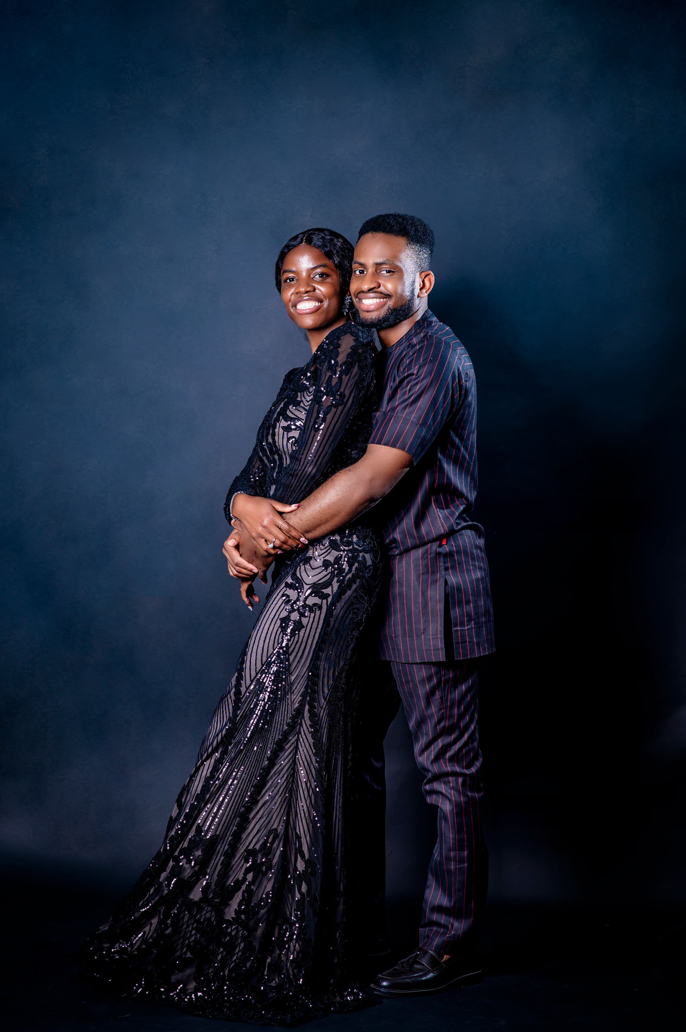 David embracing Esther from behind, she in a black lace gown, he in pinstripes