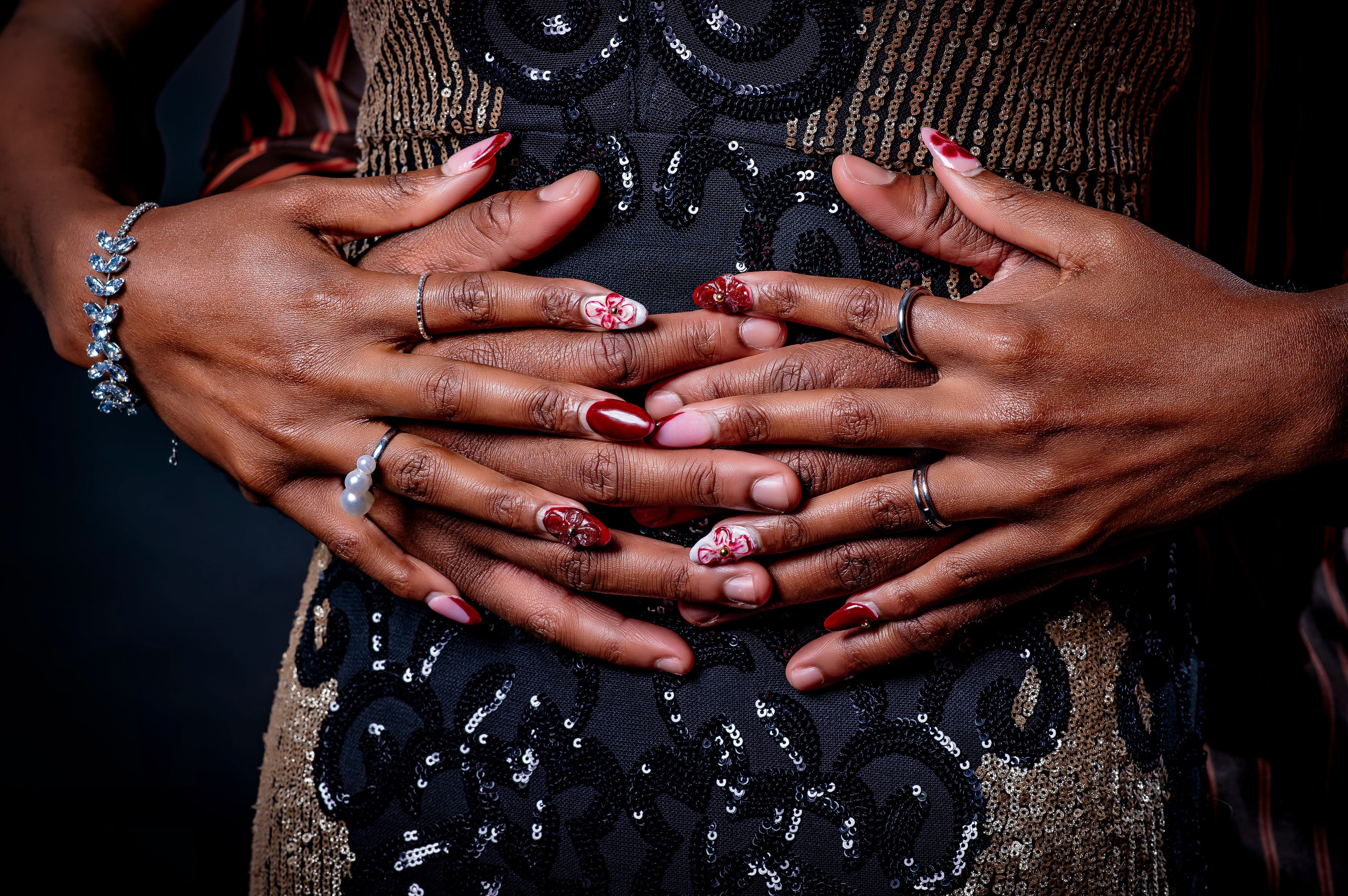 Close-up of David and Esther's hands interlaced over a sequinned gown